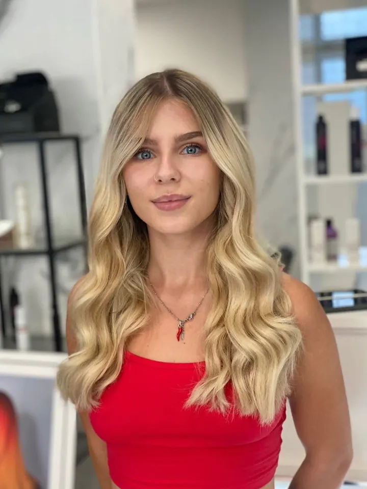 Cliente con i capelli lunghi biondi mossi, appena uscita dal salone