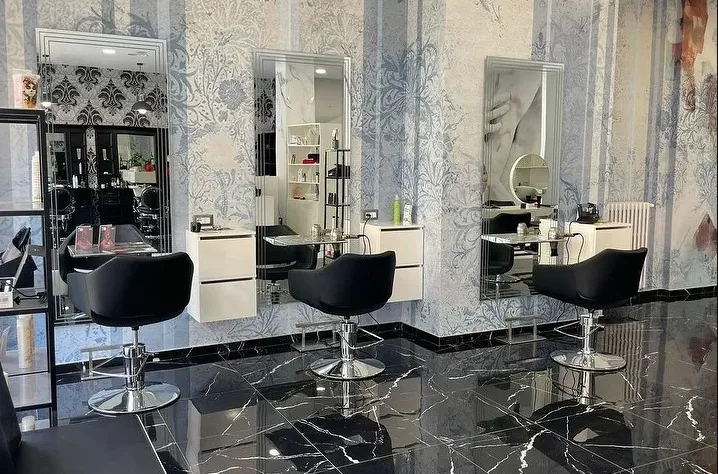 L'interno del salone di viale Stelvio: specchi, poltrone nere e carta da parati a fiori azzurri